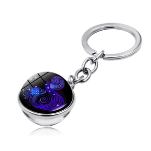 Close-up of Aquarius zodiac keychain with double-sided glass orb and silver metal ring