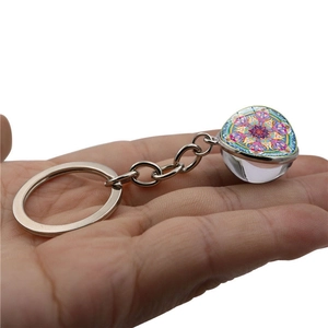 Portachiavi con sfera di vetro mandala e anello in metallo argento tenuto in mano