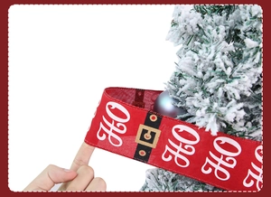 Detail of red Christmas ribbon with white HO HO HO text and Santa belt print on a tree