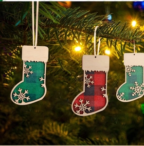 Detail of wooden Christmas stocking ornaments with red plaid and snowflakes hanging on a tree
