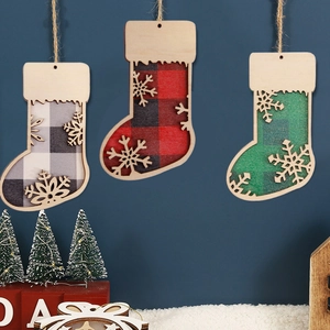 Three wooden Christmas stocking ornaments with buffalo plaid fabric and snowflake details