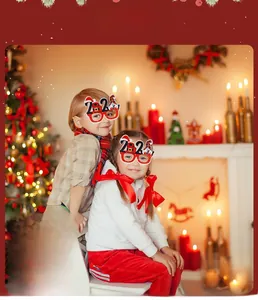 Child wearing red 2024 Christmas glasses with snowman and Santa hat in cozy holiday setting