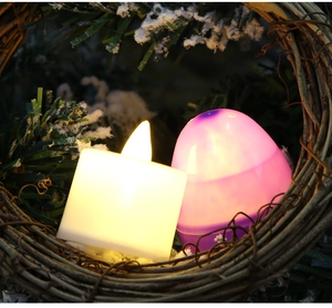 Close-up of LED glowing Easter eggs and square candle lights nested in artificial snow