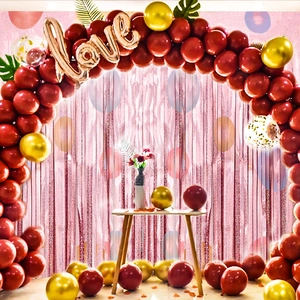 Detalle de arco de globos rojo y dorado con globo Love y cortina de lluvia rosa brillante