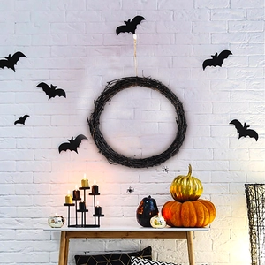 Halloween black branch wreath on white brick wall with bat stickers and pumpkins