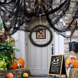 Halloween black grapevine wreath hanging on a white front door with festive decorations