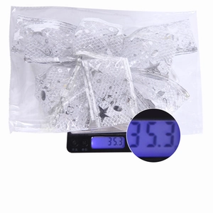 Silver bow ornament with star patterns on a digital scale showing weight of 35.3g