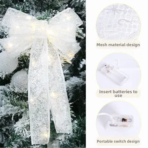 Detail of LED glowing white Christmas bow with star mesh and battery pack controls