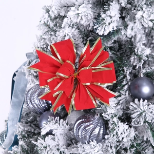 Lazo navideño de terciopelo rojo con borde dorado en una rama de árbol nevada