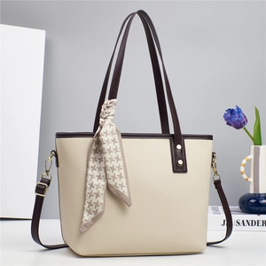 Detail of beige lychee textured bucket bag with dark brown straps and houndstooth silk scarf