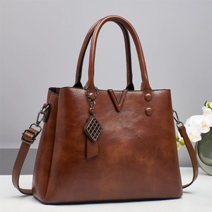 Sac à main rétro en cuir marron foncé avec détails métalliques en V et poignées