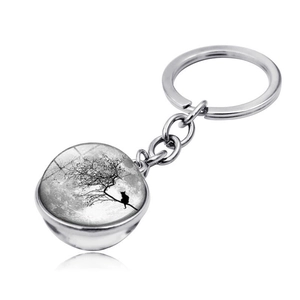 Close-up of a silver keychain featuring a black cat silhouette and moon glass pendant
