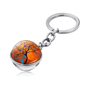 Detail of double-sided glass dome keychain featuring a colorful Tree of Life art design