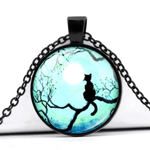 Détail du pendentif en verre avec silhouette de chat noir sur une branche sous la lune