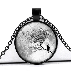 Vue macro du pendentif lune bleue et chat sur une branche noire sous cabochon