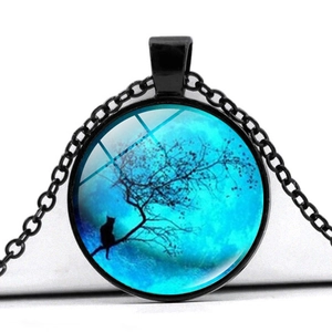 Gros plan du pendentif en verre avec lune bleue, silhouette de chat et branche d'arbre