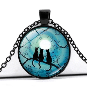 Détail macro du pendentif en verre avec arbre et chats sur chaîne noire