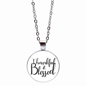 Close-up of circular silver necklace pendant featuring Thankful & Blessed text