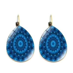 Macro detail of teardrop mandala drop earrings with blue patterns and gold metal base
