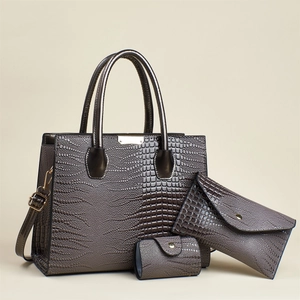 Close-up of lizard pattern texture on three-piece grey handbag set with bronze hardware