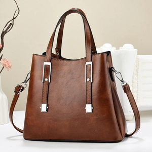 Detailed shot of brown leather tote bag with silver metal bar and adjustable strap