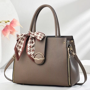 Gros plan du sac à main marron rayé avec boucle dorée et détail de foulard en soie pied-de-poule