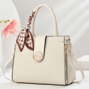 Detail of off-white crossbody bag with gold hardware and houndstooth scarf wrap handle
