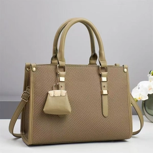 Close-up of olive green woven bucket bag with smooth leather strap and gold buckle