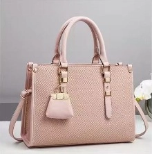Detailed view of pink textured canvas bucket bag with gold hardware and top handles