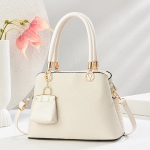 Minimalist beige woven texture tote bag with gold V logo and mini charm pendant