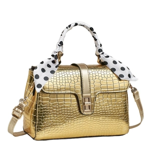 Sac à main doré texture crocodile avec foulard à pois et fermoir rotatif en métal