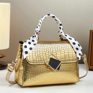Detail der goldenen Handtasche mit Steinmuster, Seidenschal-Griff und Metallschnalle