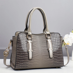 Close-up of crocodile embossed texture on a taupe tote bag with golden hardware