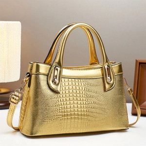 Detailed close-up of golden crocodile pattern handbag with luxury metal hardware and strap