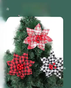 Detail of buffalo plaid Christmas poinsettia flowers with red berries on pine needles