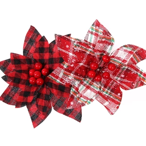 Detail of fabric poinsettia flowers with plaid patterns and red berry center accents