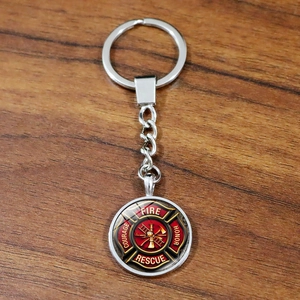 Silver firefighter fire rescue keychain with maltese cross pendant on wood surface