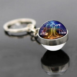 Macro shot of Libra zodiac glass ball pendant with silver ring on black surface