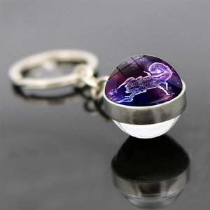 Macro detail of Scorpio zodiac sign glass ball keychain with purple starry sky and silver base
