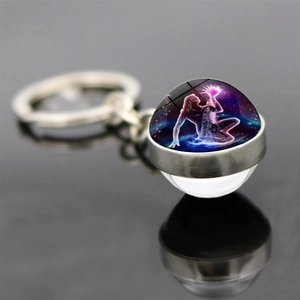 Macro shot of glass ball keychain with Aquarius zodiac goddess on a reflective surface