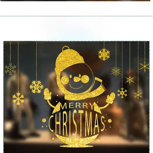 Close-up of golden glitter Christmas window stickers featuring snowman and snowflakes