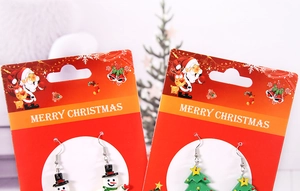Dettaglio di orecchini a pupazzo di neve e albero di Natale su carta festiva