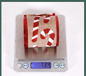 Christmas ribbon with candy cane print weighing 73.4g on a digital scale tool