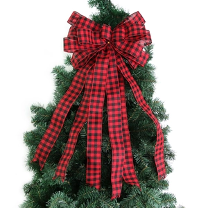 Weihnachtsbaumspitze mit rot-schwarz karierter Schleife und langen Bändern auf Tannenzweig
