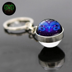 Macro shot of Aries zodiac glowing glass ball keychain with silver metal clip