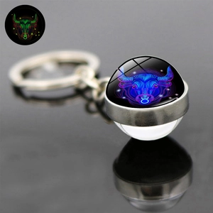 Macro view of Taurus luminous metal keychain with double-sided glass ball on black surface