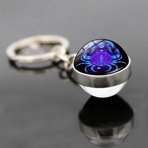 Macro shot of Cancer zodiac keychain featuring a glowing blue glass orb on a mirrored surface