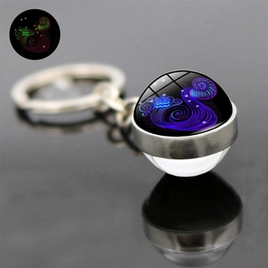 Luminous twelve constellations keychain with glowing glass ball on dark background