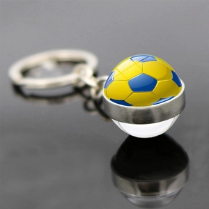 Macro d'un porte-clés football argenté avec motif jaune et bleu sur une surface noire