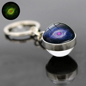 Close-up of luminous glass ball keychain featuring a glowing purple nebula and galaxy pattern